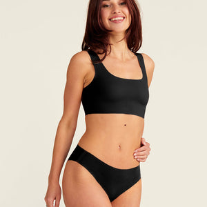Modell trägt ooia everyday Slip Seamless in Schwarz – nahtlose Unterwäsche, die Slipeinlagen ersetzt.