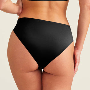 Modell trägt ooia everyday Slip Seamless in Schwarz – nahtlose Unterwäsche, die Slipeinlagen ersetzt. Rückansicht.