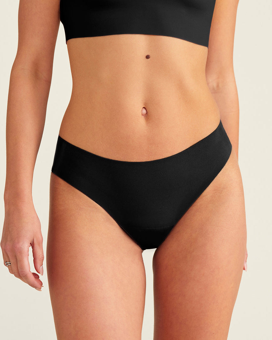 Modell trägt ooia everyday Slip Seamless in Schwarz – nahtlose Unterwäsche, die Slipeinlagen ersetzt.
