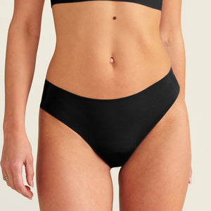 Modell trägt ooia everyday Slip Seamless in Schwarz – nahtlose Unterwäsche, die Slipeinlagen ersetzt.
