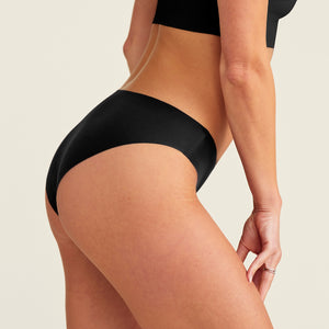 Modell trägt ooia everyday Slip Seamless in Schwarz – nahtlose Unterwäsche, die Slipeinlagen ersetzt.