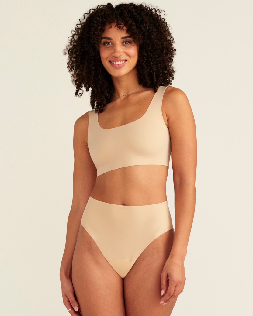 Modell trägt ooia Perioden Highwaist Seamless Cheeky in Beige – nahtloser Slip mit hoher Taille und Beinausschnitt