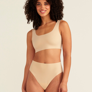 Modell trägt ooia Perioden Highwaist Seamless Cheeky in Beige – nahtloser Slip mit hoher Taille und Beinausschnitt