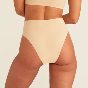 Modell trägt ooia Perioden Highwaist Seamless Cheeky in Beige – nahtloser Slip mit hoher Taille und Beinausschnitt, Rückansicht