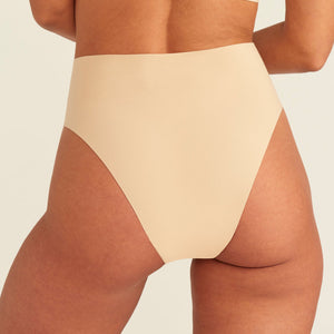 Modell trägt ooia Perioden Highwaist Seamless Cheeky in Beige – nahtloser Slip mit hoher Taille und Beinausschnitt, Rückansicht