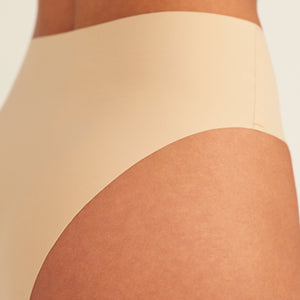 Modell trägt ooia Perioden Highwaist Seamless Cheeky in Beige – nahtloser Slip mit hoher Taille und Beinausschnitt, Detailansicht nahtloses Design
