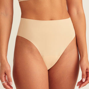 Modell trägt ooia Perioden Highwaist Seamless Cheeky in Beige – nahtloser Slip mit hoher Taille und Beinausschnitt