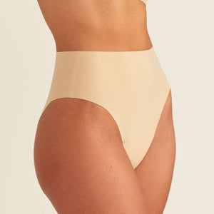 Modell trägt ooia Perioden Highwaist Seamless Cheeky in Beige – nahtloser Slip mit hoher Taille und Beinausschnitt