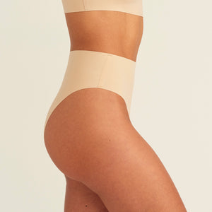 Modell trägt ooia Perioden Highwaist Seamless Cheeky in Beige – nahtloser Slip mit hoher Taille und Beinausschnitt