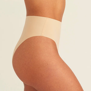 Modell trägt ooia Perioden Highwaist Seamless Cheeky in Beige – nahtloser Slip mit hoher Taille und Beinausschnitt