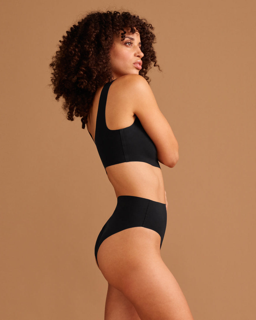 Modell trägt ooia Highwaist Seamless Cheeky in Schwarz – nahtloser Slip mit hoher Taille