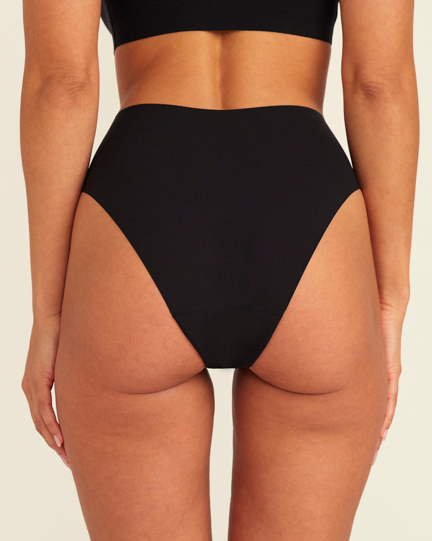 Modell trägt ooia Highwaist Seamless Cheeky in Schwarz – nahtloser Slip mit hoher Taille und Beinausschnitt, Rückansicht