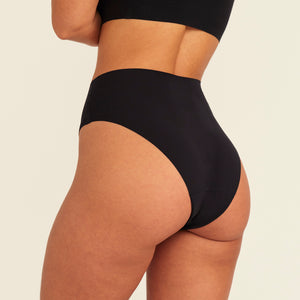 Modell trägt ooia Highwaist Seamless Cheeky in Schwarz – nahtloser Slip mit hoher Taille und Beinausschnitt, Rückansicht