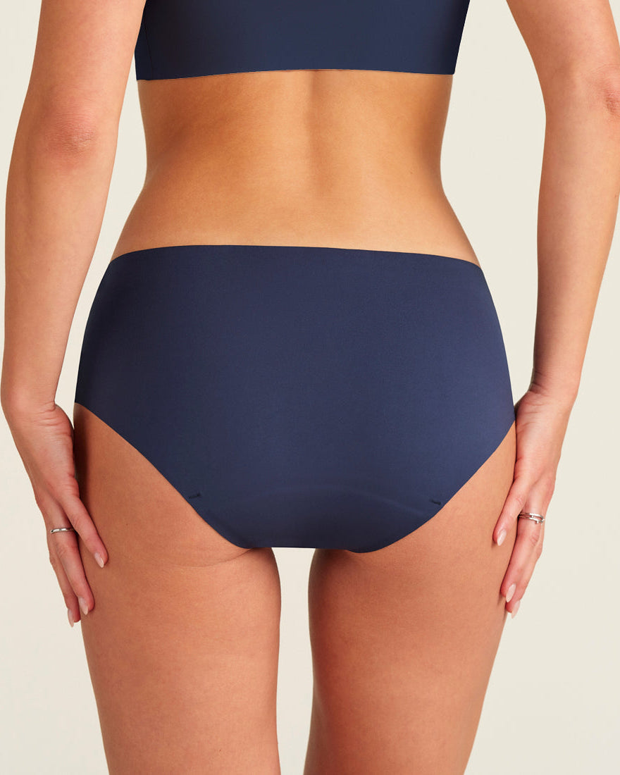 Modell trägt ooia Periodenunterwäsche Hipster Seamless Extra Strong in midnight mit nahtlosem Deign, Rückansicht