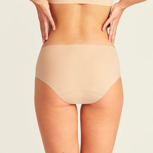 Modell trägt nahtlose ooia Periodenunterwäsche Hipster Seamless Extra Strong in beige. Rückansicht.