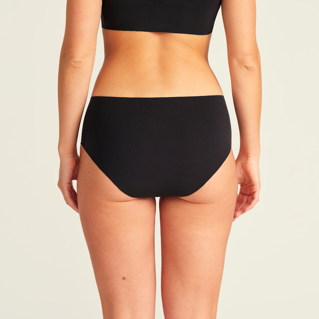 Modell trägt ooia Hipster Seamless Extra Strong in Schwarz – nahtlose Unterwäsche für eine starke Periode, Rückansicht