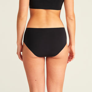 Modell trägt ooia Hipster Seamless Extra Strong in Schwarz – nahtlose Unterwäsche für eine starke Periode, Rückansicht