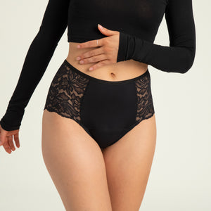 Modell trägt ooia Highwaist Lace Extra Strong in Schwarz – elegante Periodenunterwäsche mit hohem Spitzenbund und Spitzeneinsätzen.