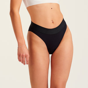 Modell trägt ooia Slip Seamless Cheeky in Schwarz – nahtlose Periodenunterwäsche mit hohem Beinausschnitt