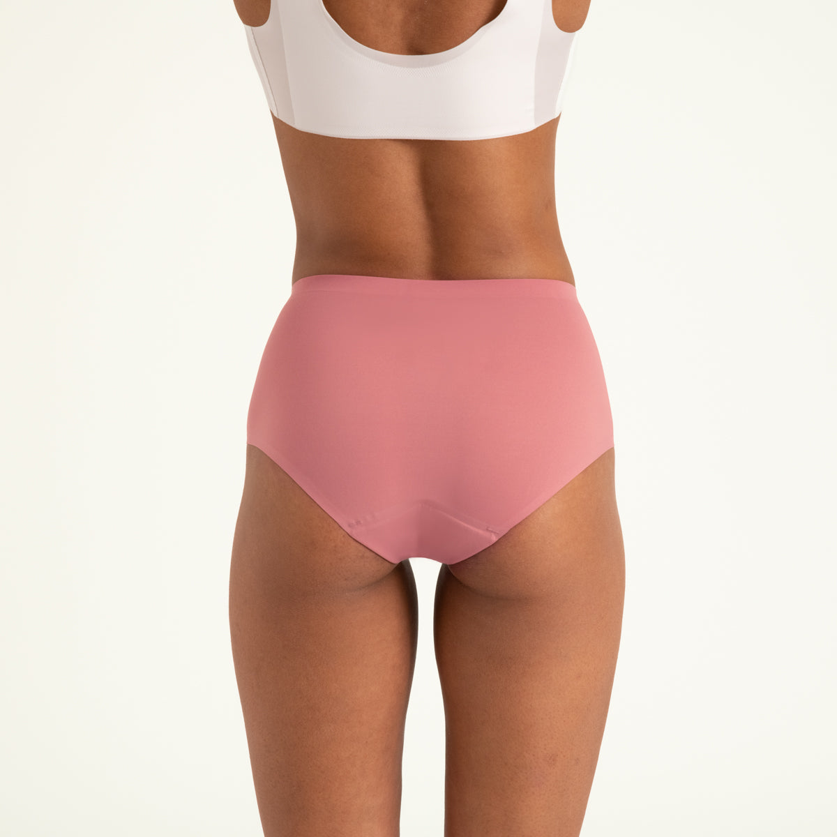 Modell trägt ooia Highwaist Seamless in Dusky Pink – nahtlose Periodenunterwäsche mit hohem Bund. Rückansicht.
