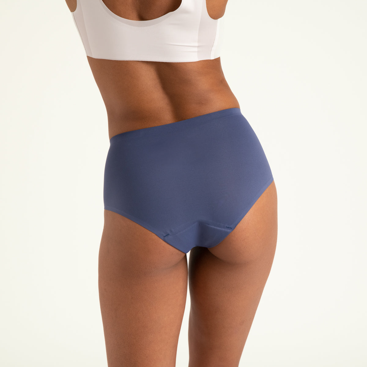 Modell trägt ooia Highwaist Seamless in Smoky Blue – nahtlose Periodenunterwäsche mit hohem Bund. Rückansicht.