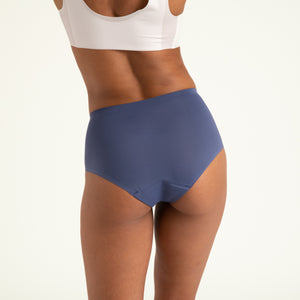 Modell trägt ooia Highwaist Seamless in Smoky Blue – nahtlose Periodenunterwäsche mit hohem Bund. Rückansicht.