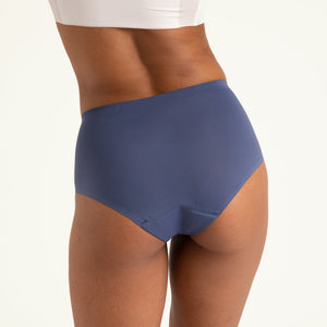 Modell trägt ooia Highwaist Seamless in Smoky Blue – nahtlose Periodenunterwäsche mit hohem Bund. Rückansicht.