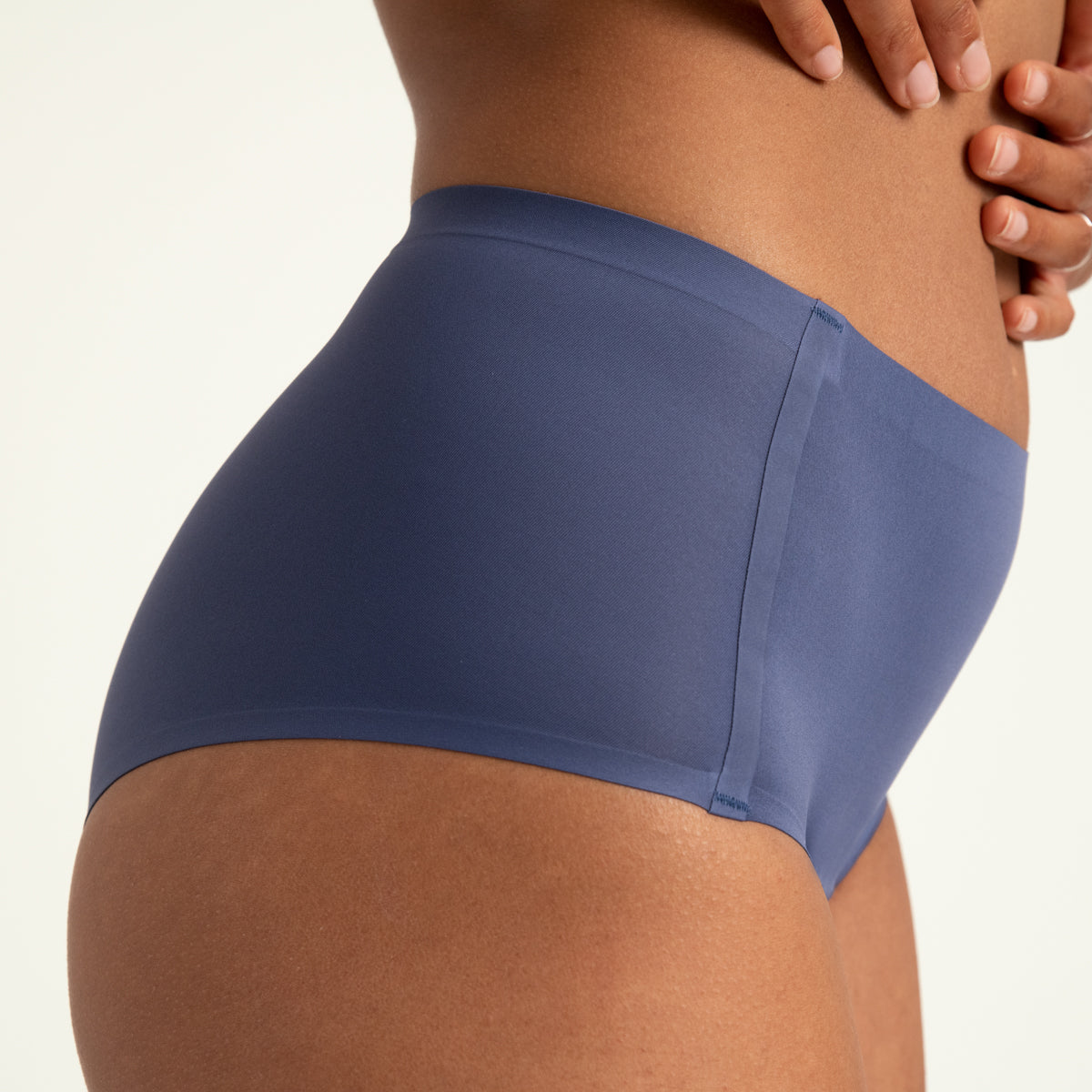 Modell trägt ooia Highwaist Seamless in Smoky Blue – nahtlose Periodenunterwäsche mit hohem Bund. Detailansicht.