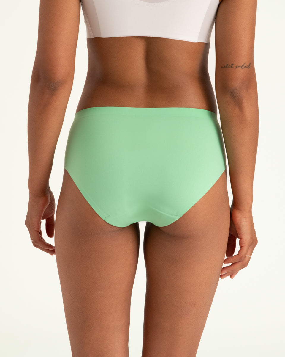Modell trägt ooia Hipster Seamless in Bright Sage – Periodenunterwäsche mit bequemer Passform und weichem, nahtlosem Stoff. Rückansicht.