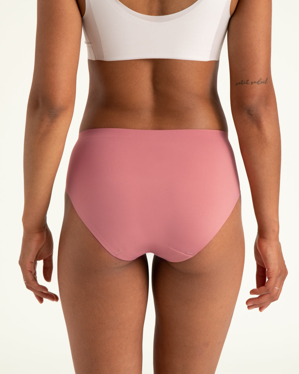 Modell trägt ooia Hipster Seamless in Dusky Pink – Periodenslip mit bequemer Passform und weichem, nahtlosem Stoff. Rückansicht.