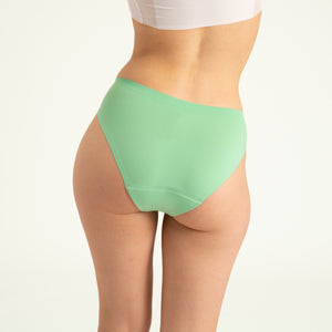 Modell trägt ooia Slip Seamless in Bright Sage – nahtlose Periodenunterwäsche im klassischen Schnitt. Rückansicht.
