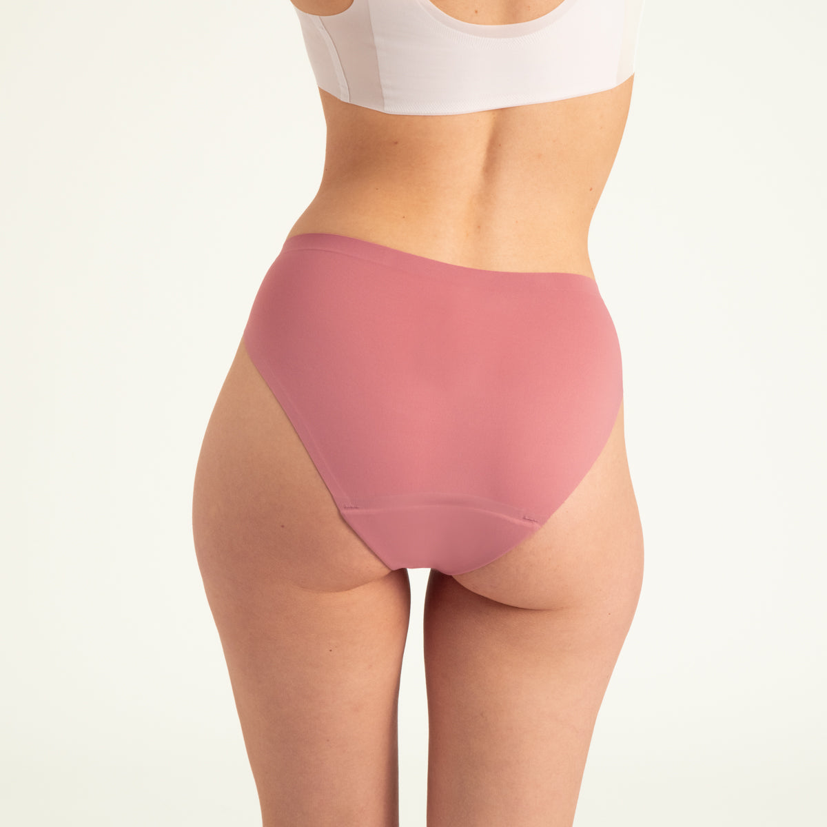 Modell trägt ooia Slip Seamless in Dusky Pink – nahtlose Periodenunterwäsche im klassischen Schnitt. Rückansicht.