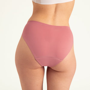 Modell trägt ooia Slip Seamless in Dusky Pink – nahtlose Periodenunterwäsche im klassischen Schnitt. Rückansicht.