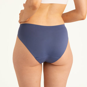 Modell trägt ooia Slip Seamless in Smoky Blue – nahtlose Periodenunterwäsche im klassischen Schnitt. Rückansicht.