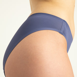 Modell trägt ooia Slip Seamless in Smoky Blue – nahtlose Periodenunterwäsche im klassischen Schnitt. Detailansicht.