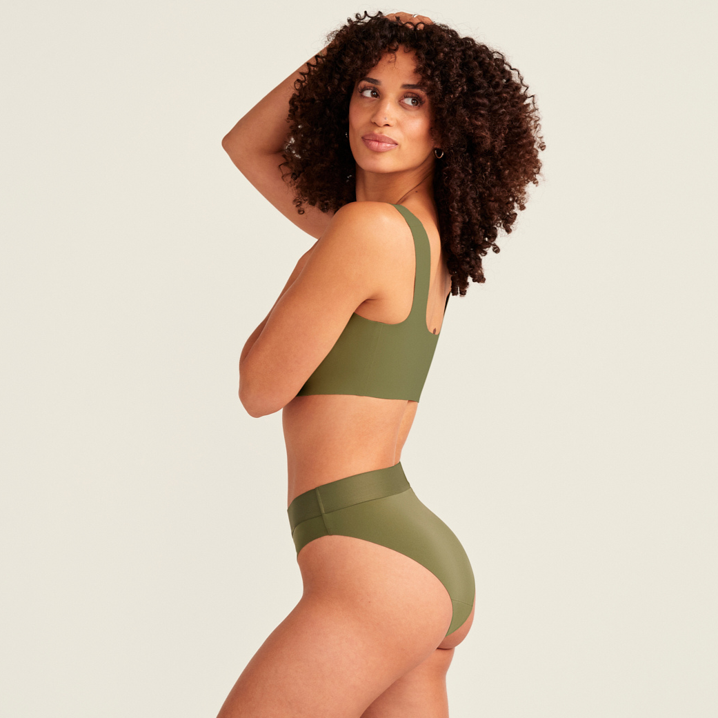 Modell trägt ooia Periodenslip Seamless Cheeky Periodenslip in Khaki mit hohem Beinausschnitt