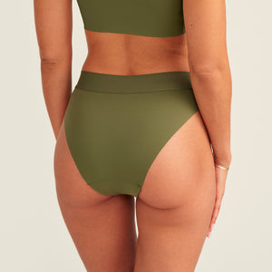 Modell trägt ooia Periodenslip Seamless Cheeky Periodenslip in Khaki mit hohem Beinausschnitt, Rückansicht