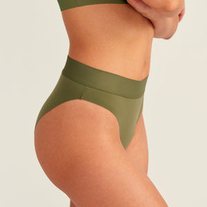 Modell trägt ooia Periodenslip Seamless Cheeky Periodenslip in Khaki mit hohem Beinausschnitt