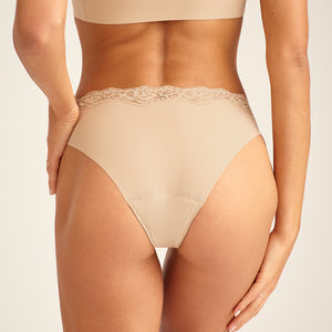 Modell trägt ooia Periodenunterwäsche Slip Seamless Lace Extra Strong in Beige, Rückansicht