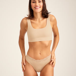 Modell trägt ooia Periodenunterwäsche Slip Seamless Lace Extra Strong in Beige
