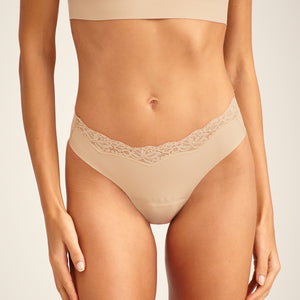Modell trägt ooia Periodenunterwäsche Slip Seamless Lace Extra Strong in Beige