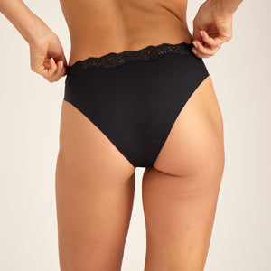Modell trägt nahtlosen ooia Periodenunterwäsche Slip Seamless Lace Extra Strong in schwarz, Rückansicht