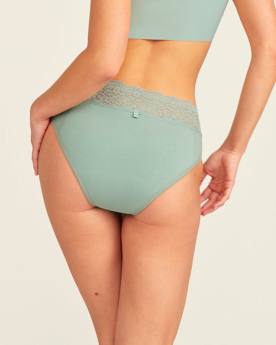 Modell trägt ooia Periodenslip in sage mit Spitze am Bund, Rückansicht.
