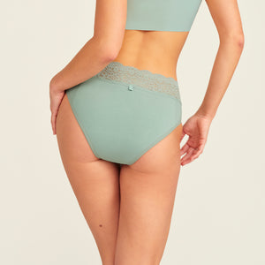 Modell trägt ooia Periodenslip in sage mit Spitze am Bund, Rückansicht.