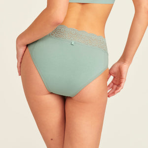 Modell trägt ooia Periodenslip in sage mit Spitze am Bund, Rückansicht.