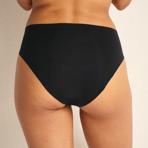 Modell trägt Periodenunterwäsche Slip Seamless Ultimate in schwarz mit nahtlosem Design.
von hinten