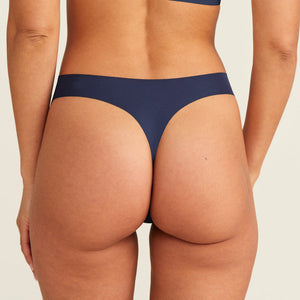 Modell trägt den ooia Periodenunterwäsche String Seamless in midnight mit leichter Saugstärke, Rückansicht