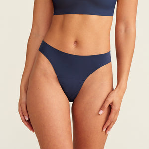 Modell trägt den ooia Periodenunterwäsche String Seamless in midnight mit leichter Saugstärke
