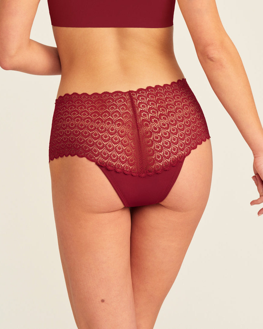 Modell trägt ooia Periodenunterwäsche Highwaist Comfy Lace in merlot, mit durchgängiger, elastischer Spitze. Rückansicht.