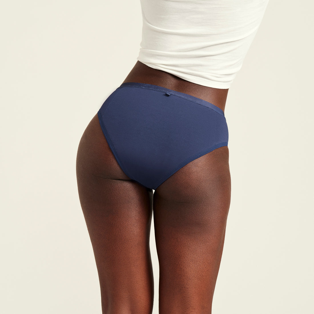 Modell trägt ooia Slip Basic Extra Strong in Midnight – Periodenunterwäsche im klassischen Schnitt mit extra starker Saugkraft. Rückansicht.